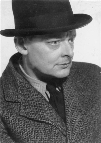 A black-and-white portrait of a man in a fedora and textured coat.