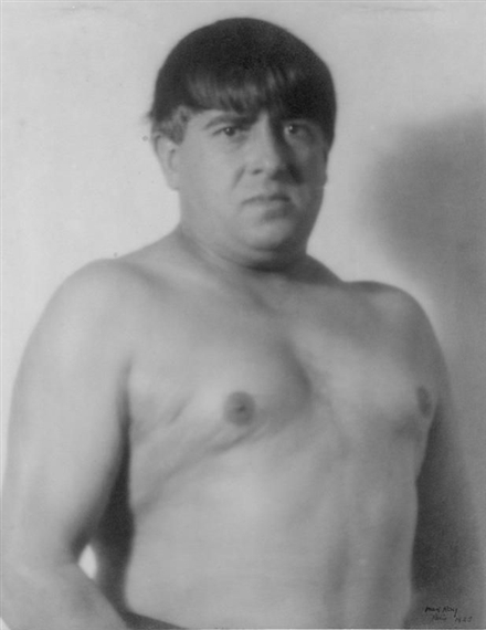 A black-and-white portrait of a shirtless figure with a solemn expression.