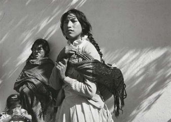 A black and white portrait captures a group of three figures against a textured wall, illuminated by strong diagonal light.