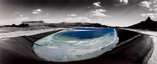 A surreal landscape featuring a large, oval-shaped body of water nestled within a dark, curved basin.