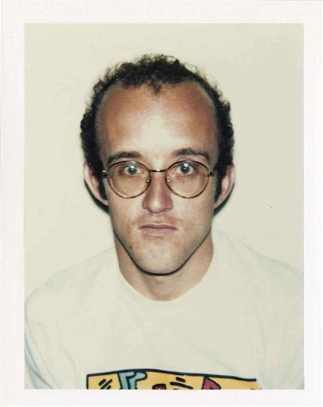 A candid Polaroid-style portrait of a person with glasses and a graphic t-shirt.