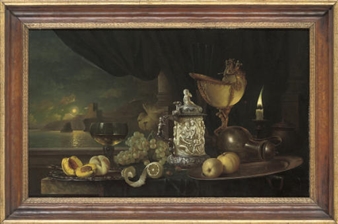 Peaches on a silver platter, with a römer, grapes, lemon, silver mounted ivory tankard, jug and a candle, on a stone ledge, a moonlit seascape beyond - Gyula Bubárnik