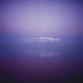 A serene seascape where a single cloud hovers over calm waters under a purple sky.