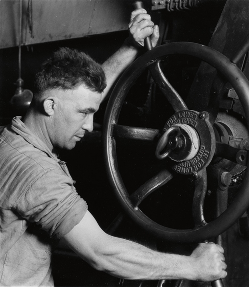 An Industrial Design, Pennsylvania Rubber Co., at the control wheel of a great 'calendar'--making auto tires by Lewis Hine, Circa 1925