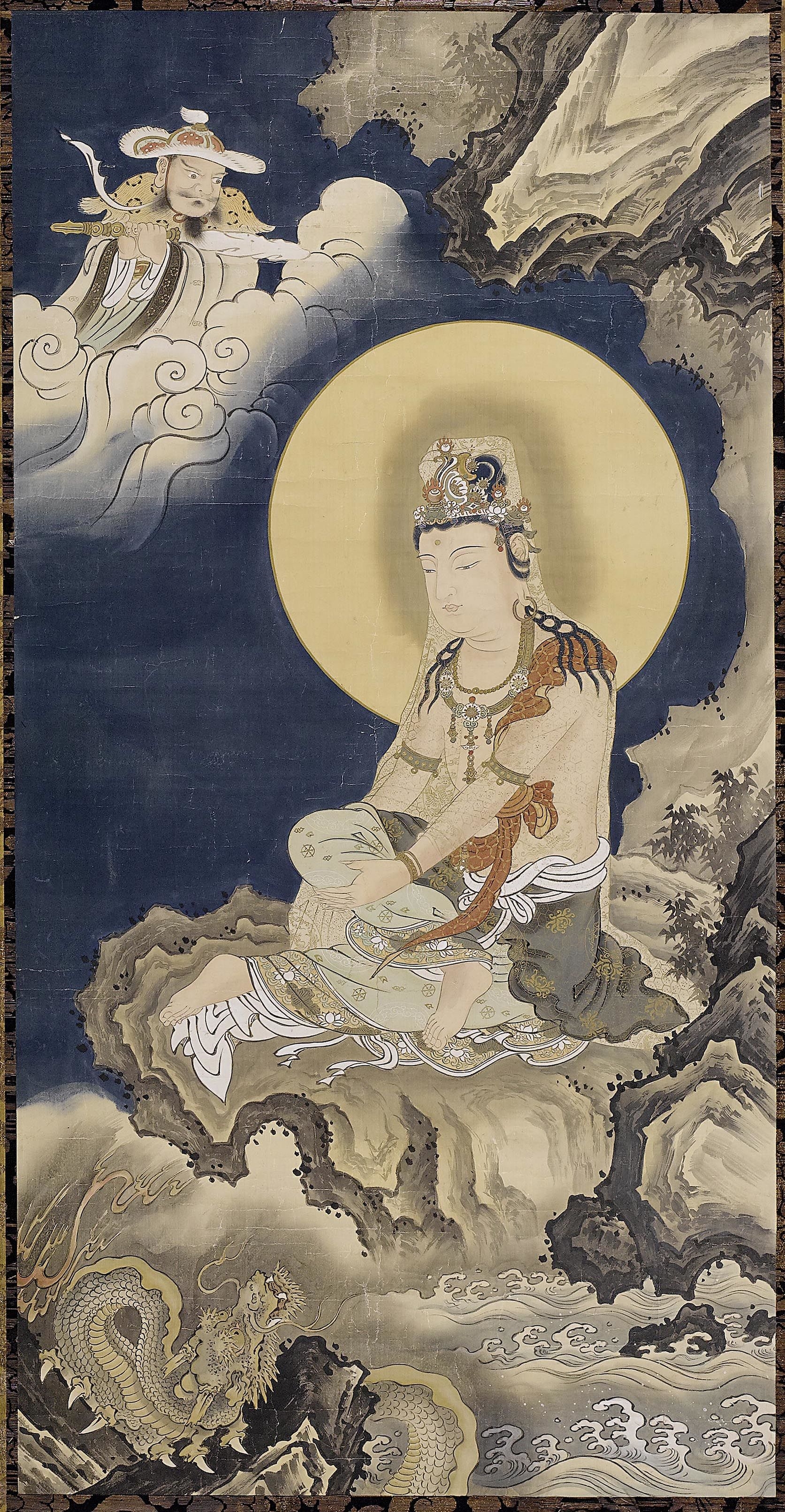 With the moon shining brightly in the background, Kannon is depicted seated on a rock, accompanied by a dragon. 
