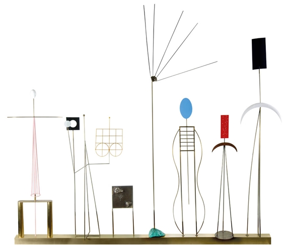 A whimsical metal sculpture featuring abstract figures and geometric shapes on a brass base.