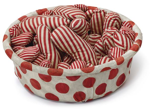 A whimsical, patterned basket overflowing with striped heart-shaped cushions.