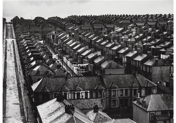 A high-angle black-and-white view of a dense, repetitive row of terraced houses.