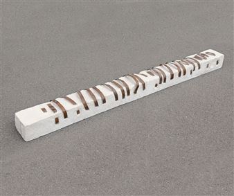 A long, white rectangular block with a series of brown, curved slits running along its length.