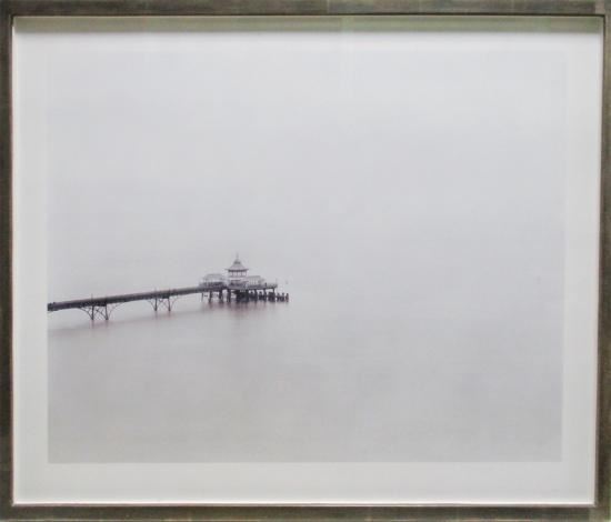 A misty seascape featuring a pier extending into a foggy expanse.