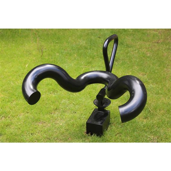 A black abstract sculpture with curved tubes and a vertical loop sits on a grassy lawn.