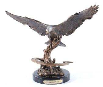 A bronze sculpture of an eagle perched on a gnarled branch, its wings spread wide against a stark white background.