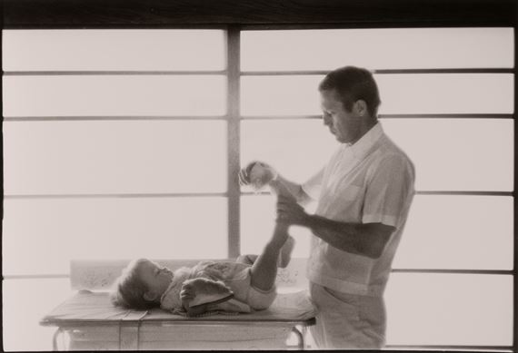Steve McQueen, Hollywood's King of Cool, putting slippers on daughter Terry at home, by Sid Avery, 1960