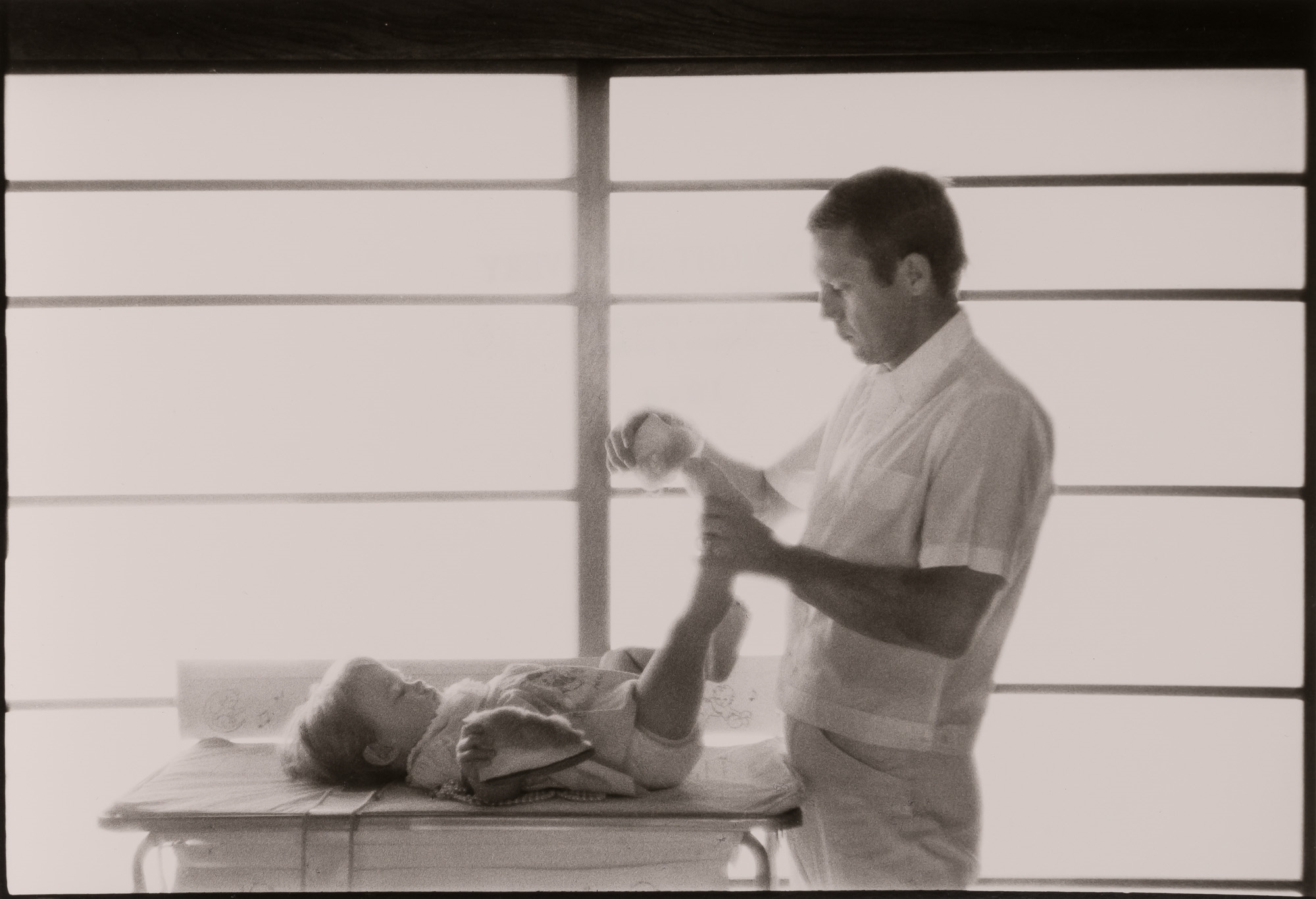 Artwork by Sid Avery, Steve McQueen, Hollywood's King of Cool, putting slippers on daughter Terry at home,, Made of Gelatin silver print