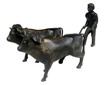 A bronze sculpture of a farmer guiding two oxen.