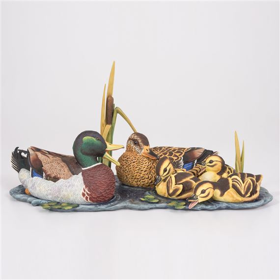 A detailed figurine of a duck family resting on a lily pad.