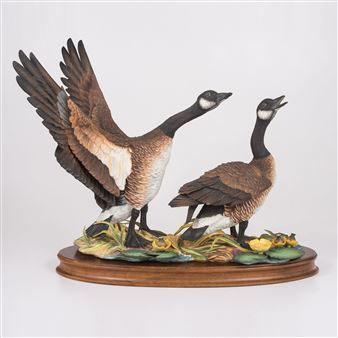 A sculptural pair of geese in dynamic poses on a naturalistic base.