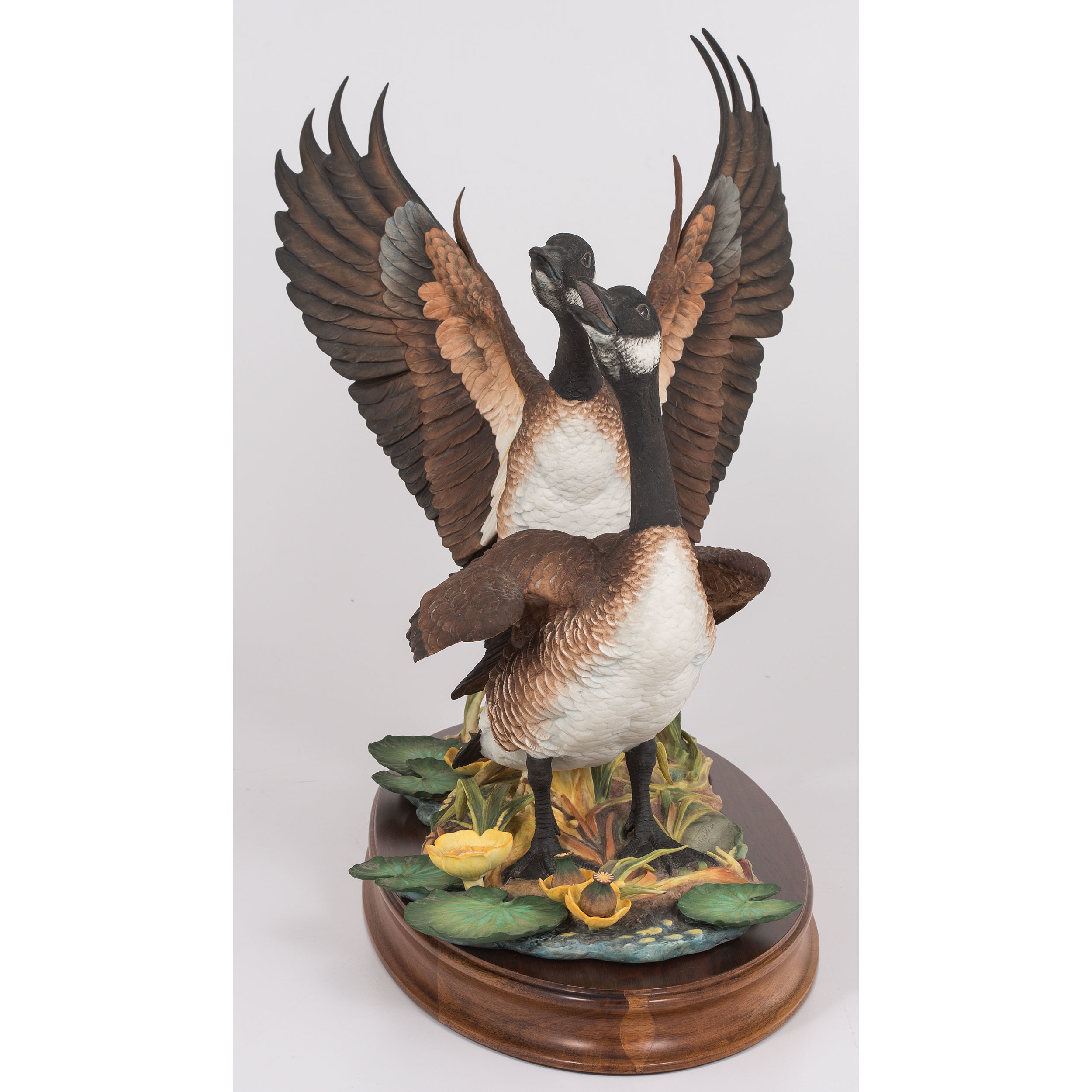 A sculptural pair of geese in dynamic poses on a naturalistic base.