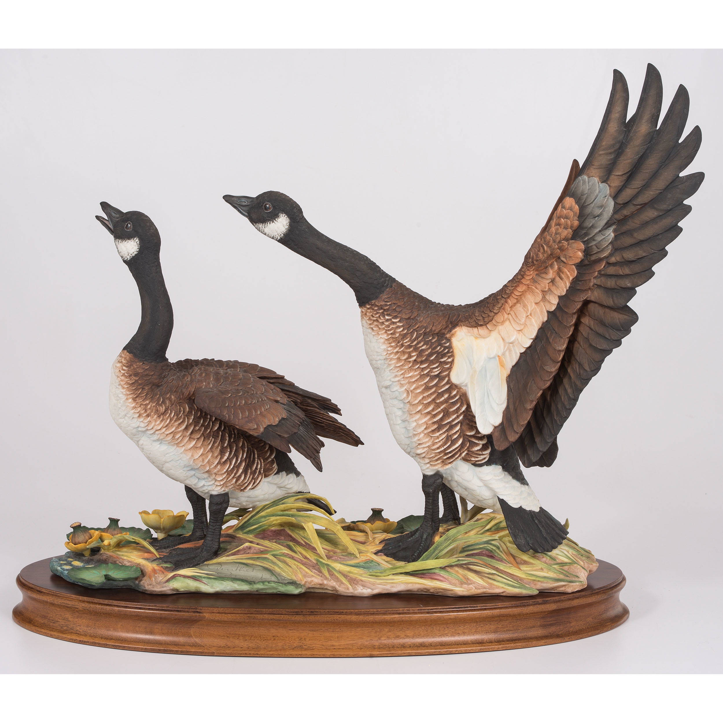 A sculptural pair of geese in dynamic poses on a naturalistic base.