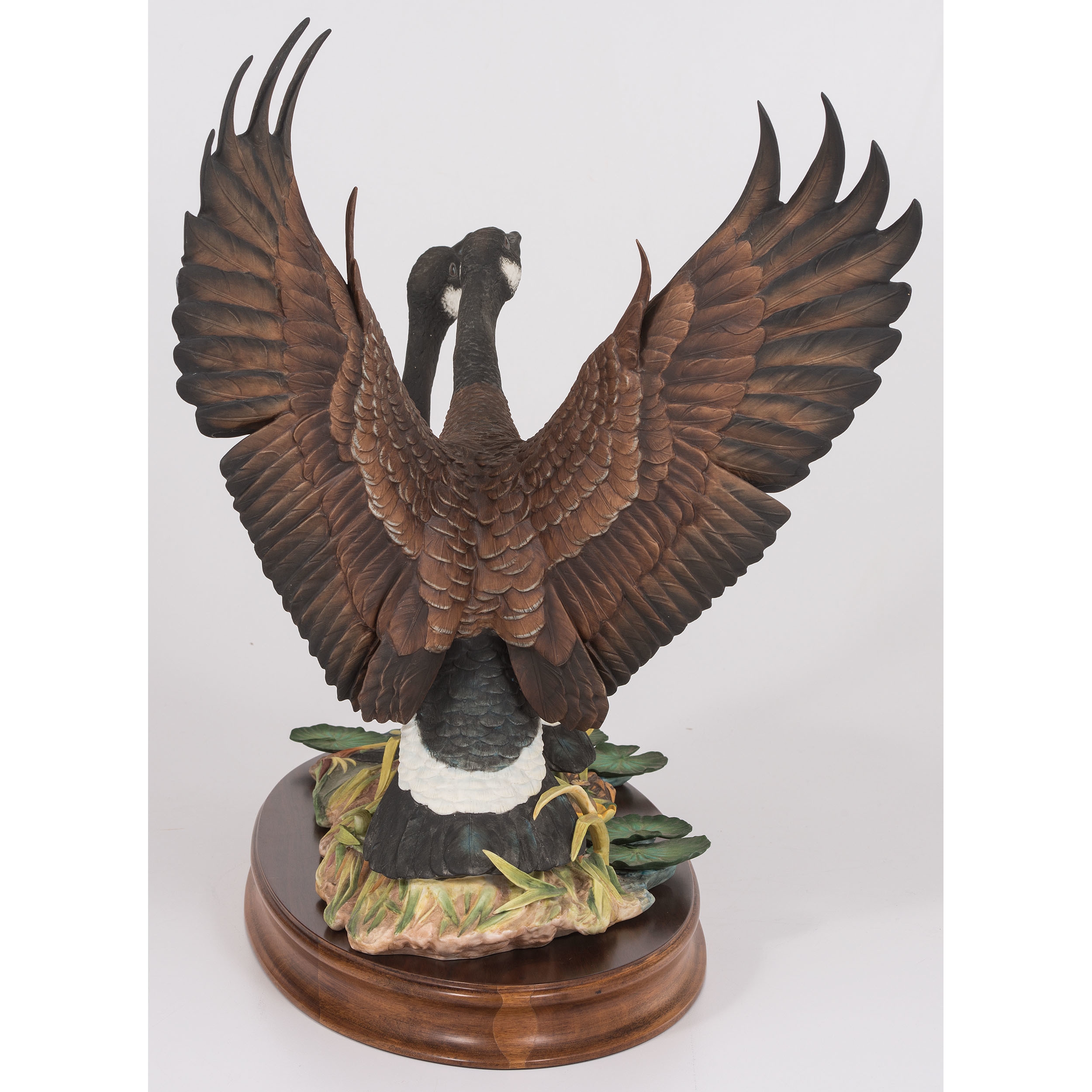 A sculptural pair of geese in dynamic poses on a naturalistic base.