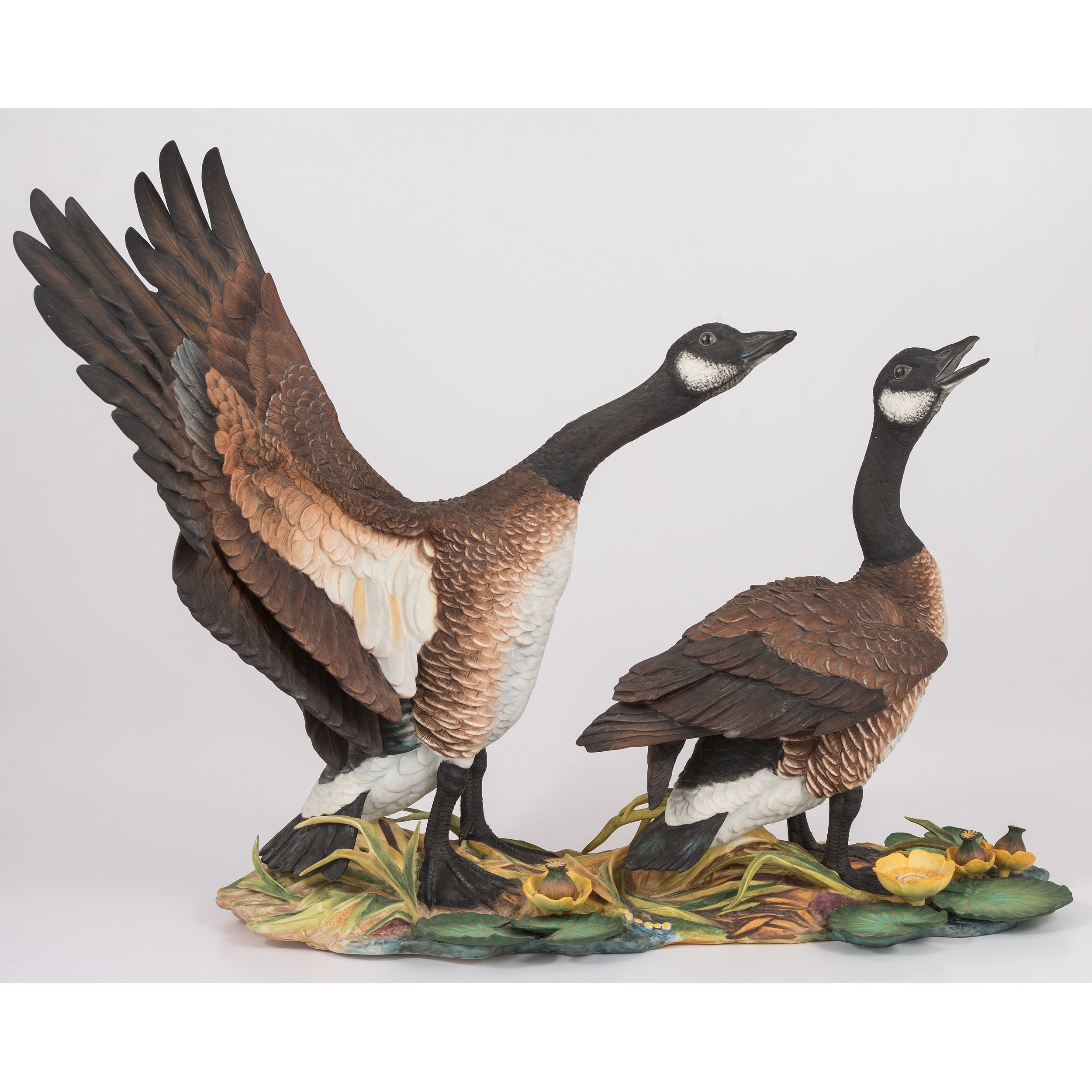 A sculptural pair of geese in dynamic poses on a naturalistic base.