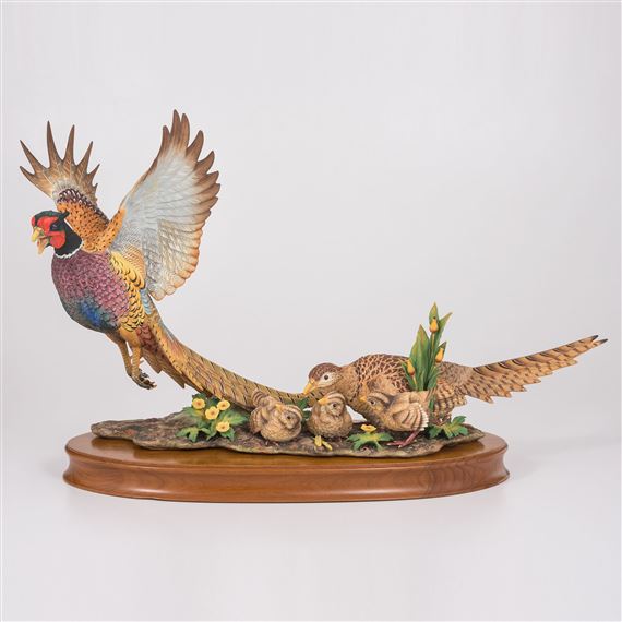 A sculptural group of pheasants in flight and rest, rendered in vibrant colors on a wooden base.