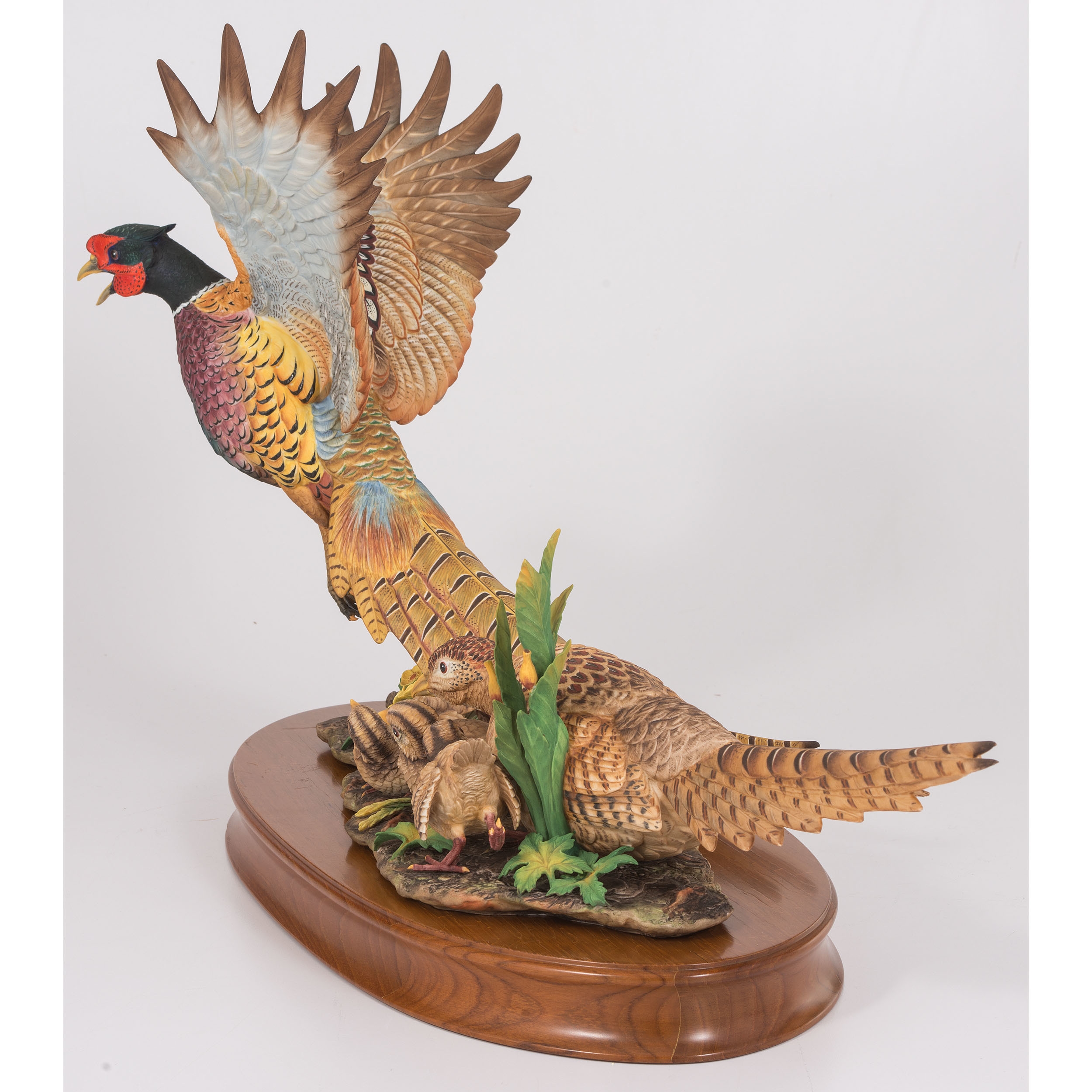 A sculptural group of pheasants in flight and rest, rendered in vibrant colors on a wooden base.
