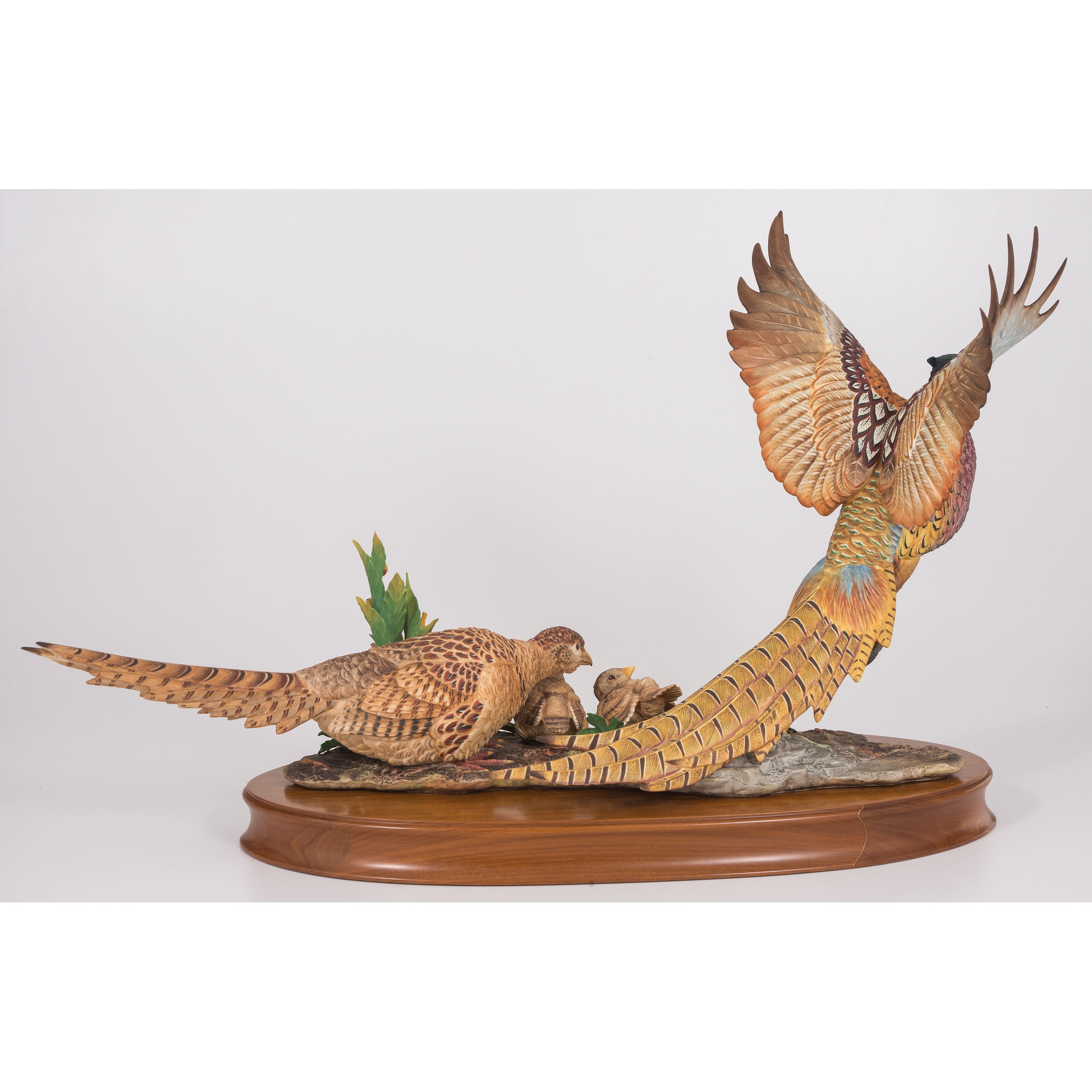 A sculptural group of pheasants in flight and rest, rendered in vibrant colors on a wooden base.