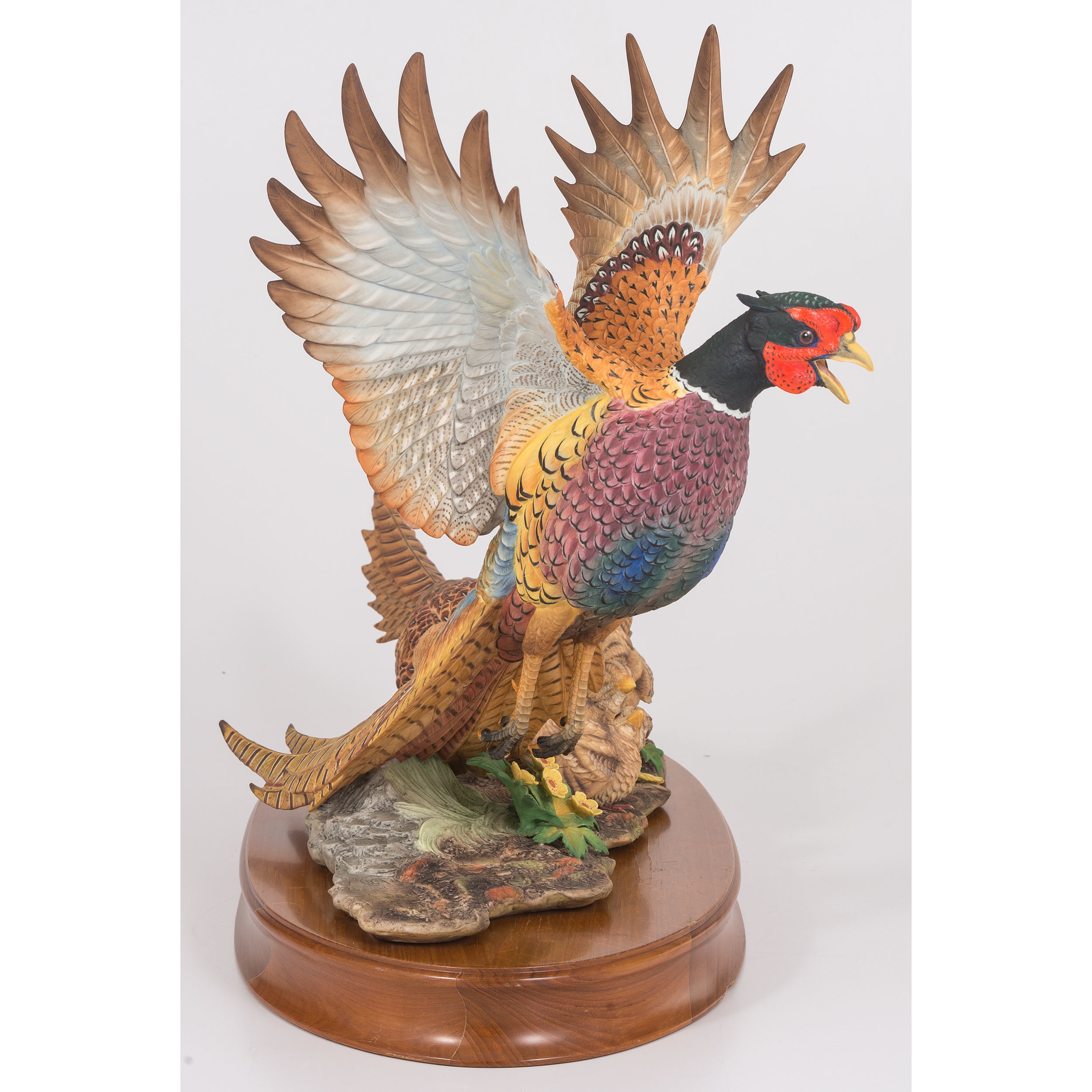 A sculptural group of pheasants in flight and rest, rendered in vibrant colors on a wooden base.