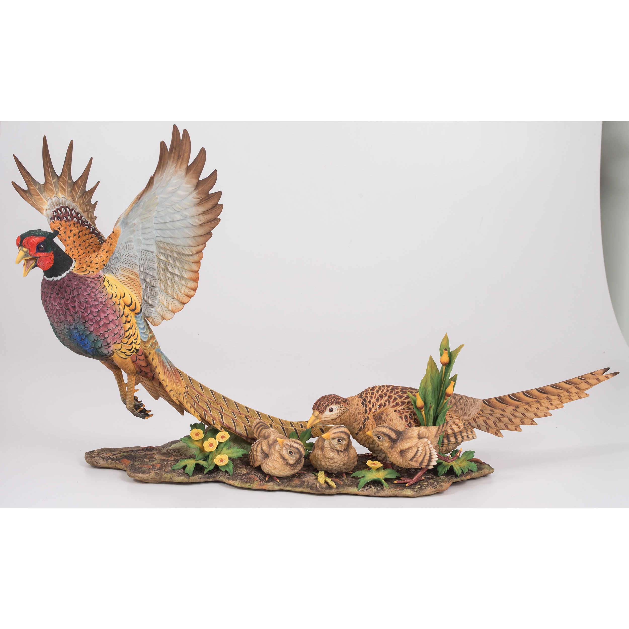 A sculptural group of pheasants in flight and rest, rendered in vibrant colors on a wooden base.