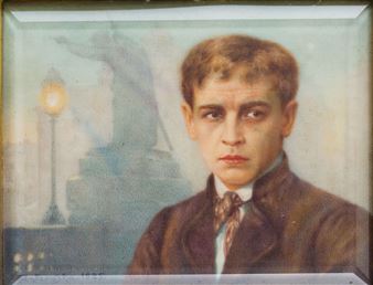 A formal portrait of a young man in a dark suit against a muted, atmospheric background.