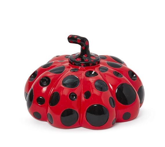 A glossy red pumpkin-shaped ceramic object covered in black spots.