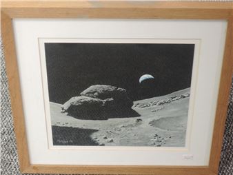 A framed black-and-white print depicting a lunar landscape with a large rock formation and a distant celestial body.
