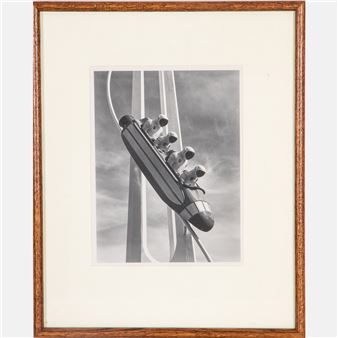 A black-and-white framed photograph of a futuristic roller coaster with multiple riders.