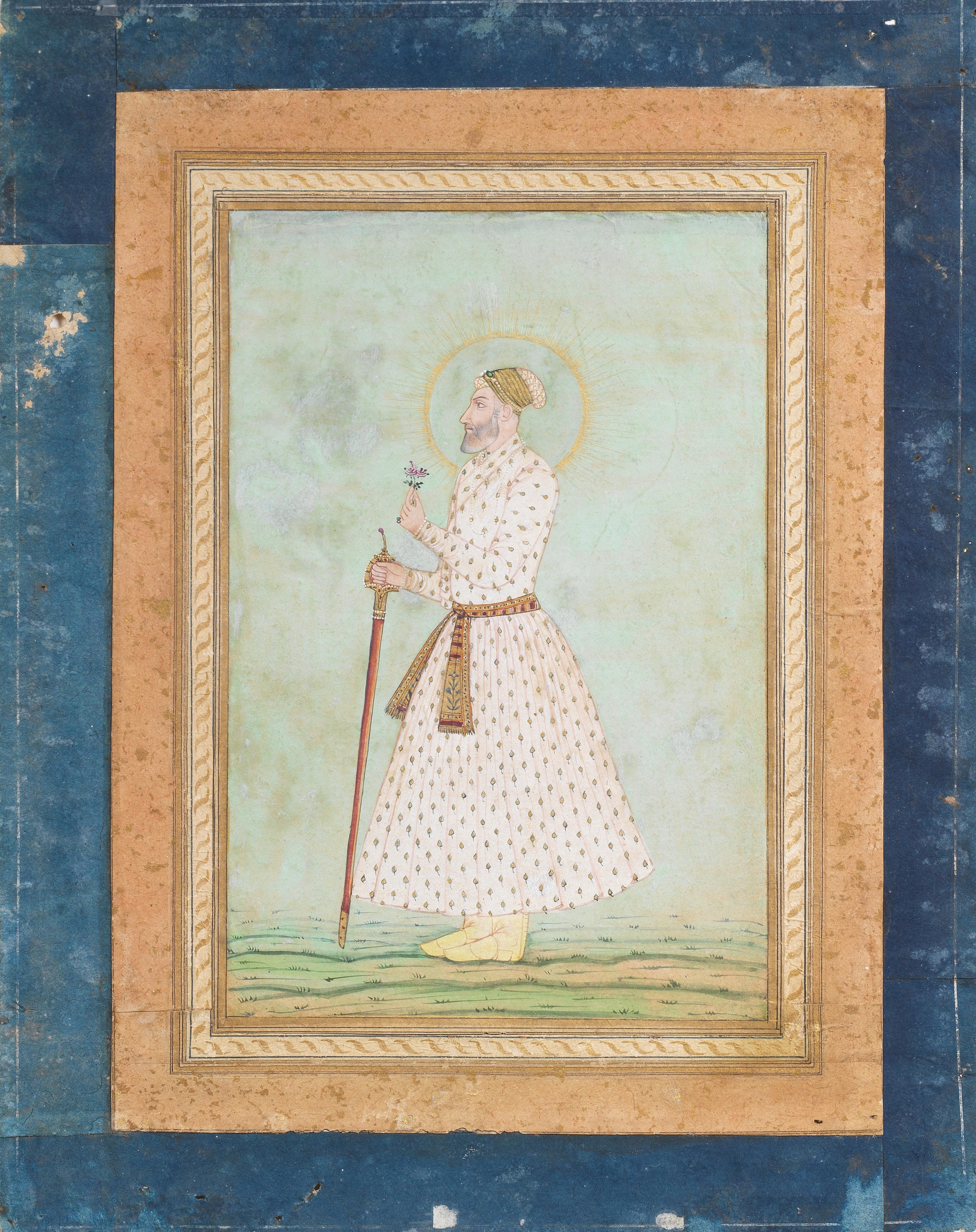 A nobleman standing in a landscape, holding a sword and a flower by Mughal School, 18th Century, late 17th/18th Century