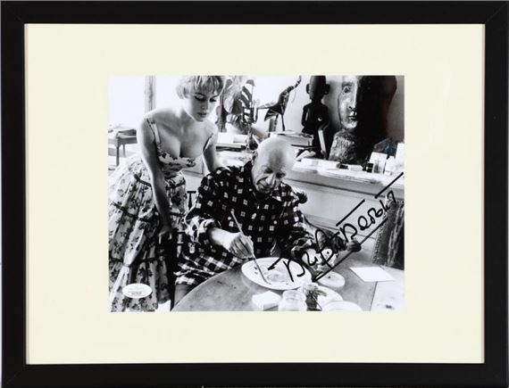 A signed b/w press photograph of the French actress Brigitte Bardot (b. 1934) in the company of the painter Pablo Picasso in his studio - Jérôme Brierre