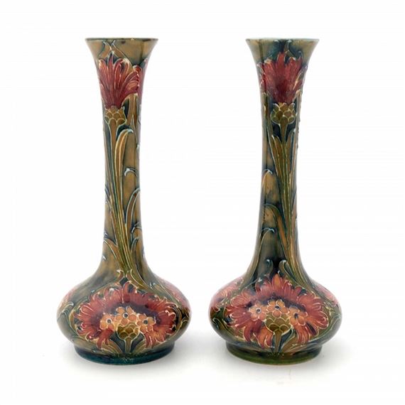 A pair of tall ceramic vases featuring floral motifs and a rich, earthy color palette.