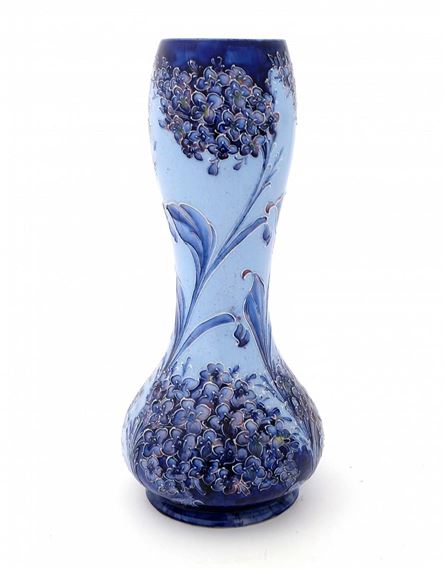 A blue ceramic vase featuring a floral design with clusters of berries and leaves.