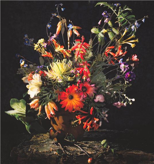 A vibrant floral still life featuring a dense bouquet of colorful flowers in a rustic pot.