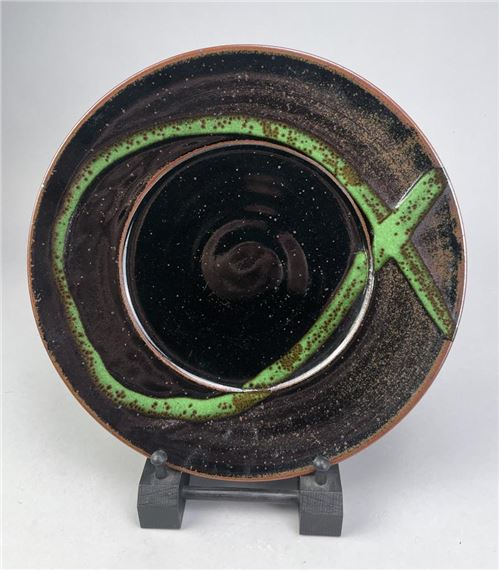 a stoneware plate covered in tenmoku breaking to kaki glaze with chrome green decoration
