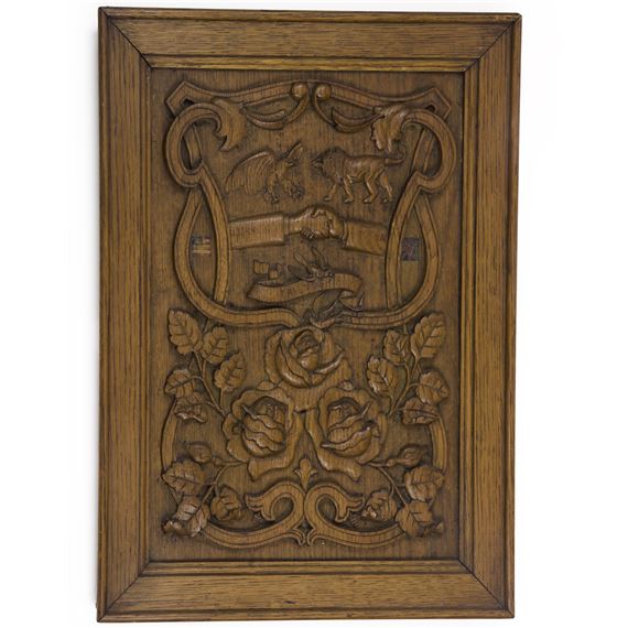 A detailed wooden relief panel featuring carved heraldic figures and floral elements.