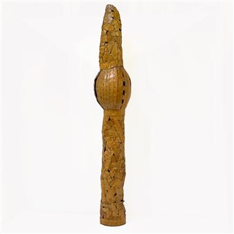 A tall, segmented wooden sculpture with a textured surface and a bulbous middle section.