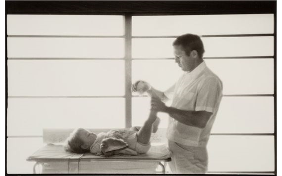Steve McQueen, Hollywood's King of Cool, putting slippers on daughter, Terry, at home by Sid Avery, 1960, printed later