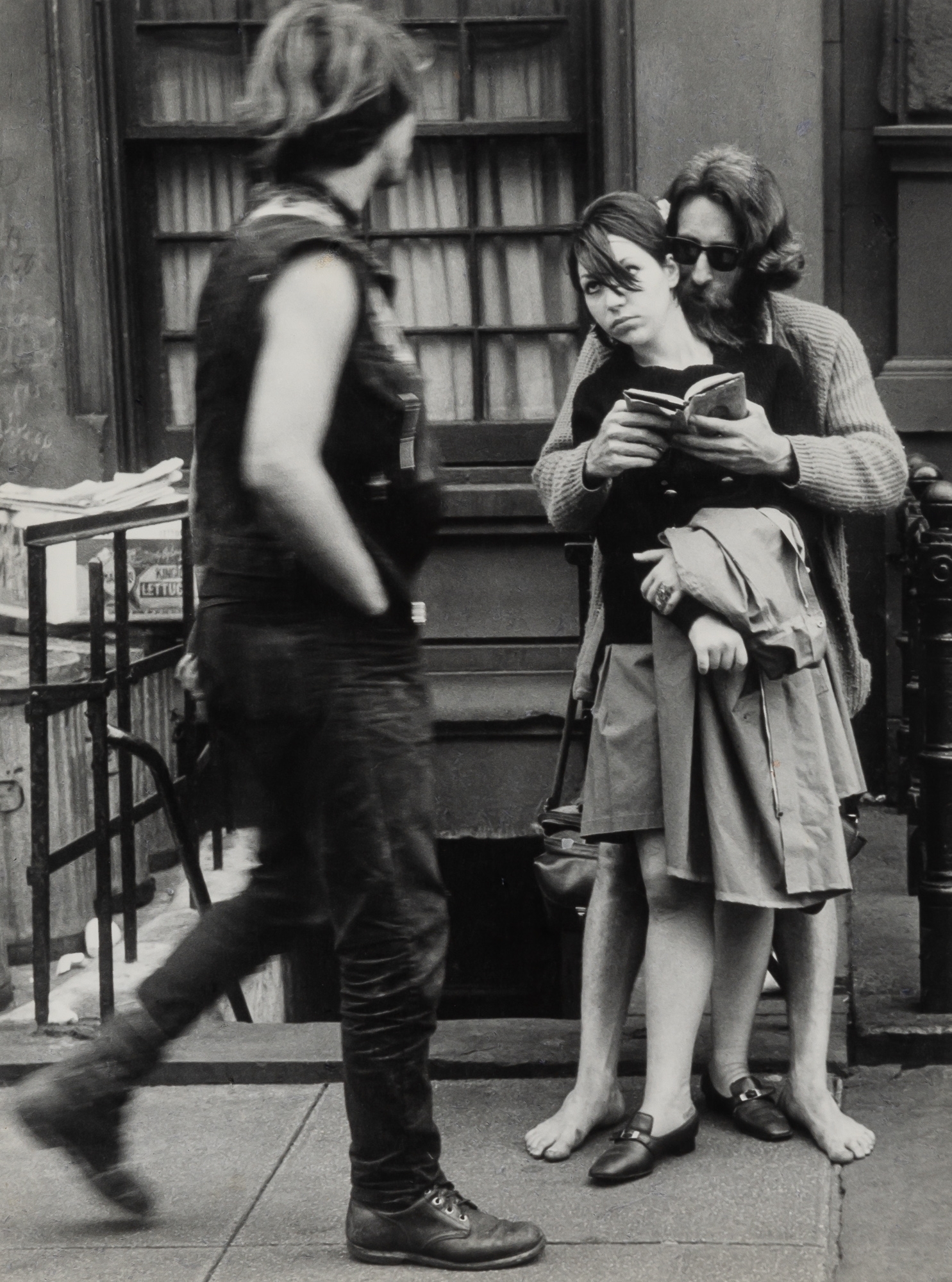 Artwork by Leon Levinstein, LEVINSTEIN, LEON (1913-1988) Untitled [couple on street, man reading to woman, barefoot],, Made of Vintage gelatin silver print