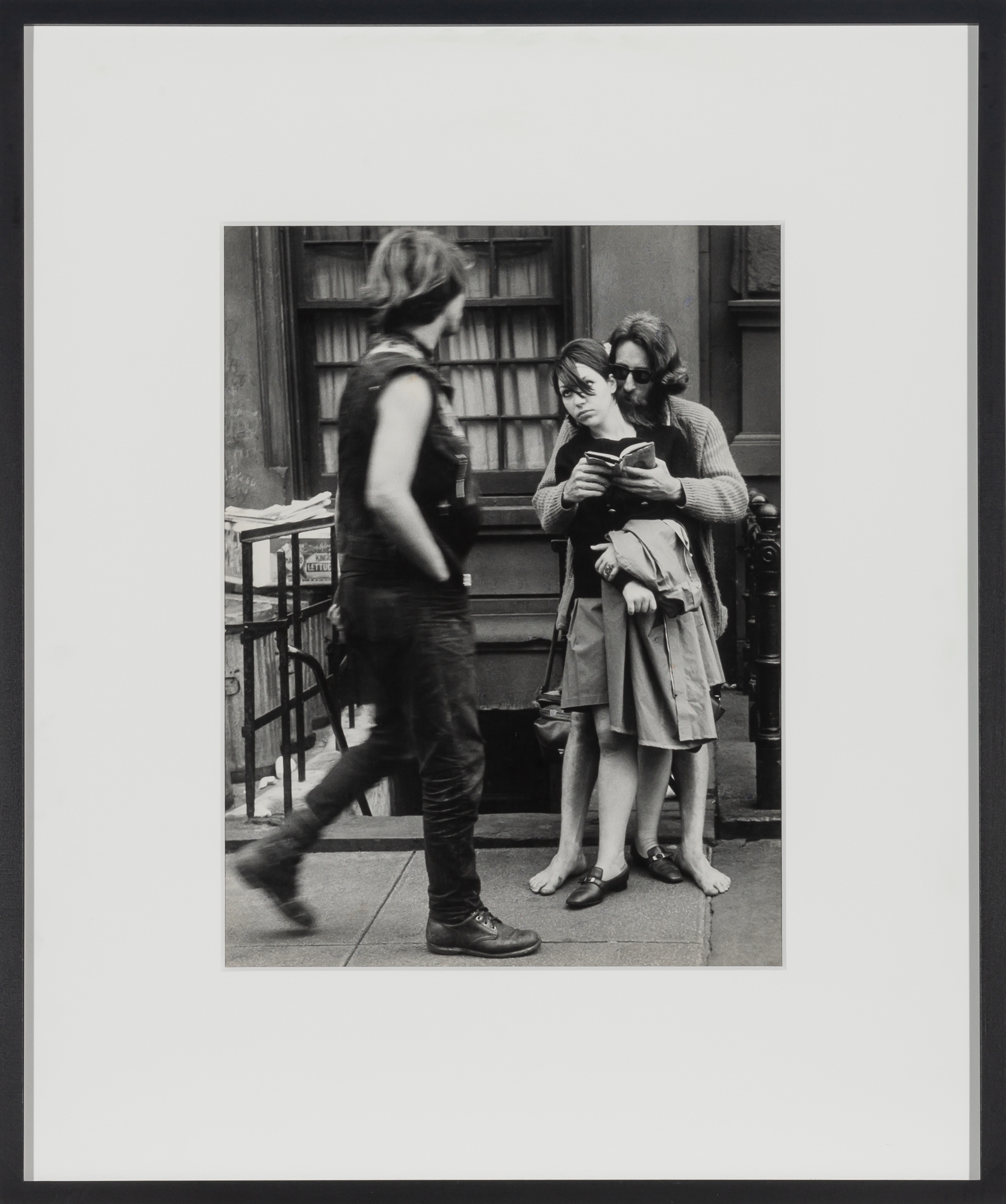 Artwork by Leon Levinstein, LEVINSTEIN, LEON (1913-1988) Untitled [couple on street, man reading to woman, barefoot],, Made of Vintage gelatin silver print