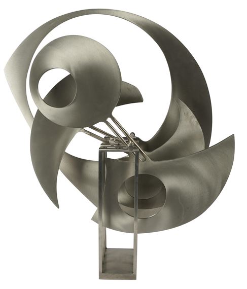 A metallic sculpture featuring abstract, curved forms mounted on a rectangular base.
