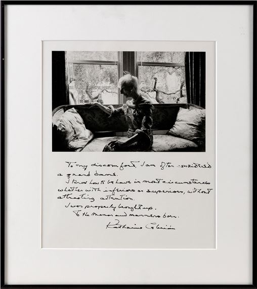 A black and white framed photograph of a person sitting on a sofa with handwritten text below.