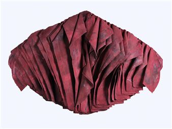 A sculptural arrangement of folded red fabric forming a layered, fan-like shape.