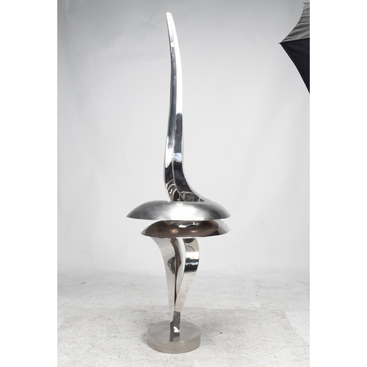 A sleek, abstract sculpture featuring a twisted metal form with a sharp, upward-pointing tip.