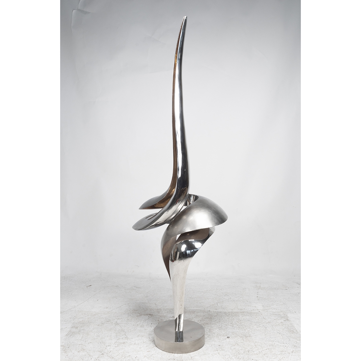 A sleek, abstract sculpture featuring a twisted metal form with a sharp, upward-pointing tip.